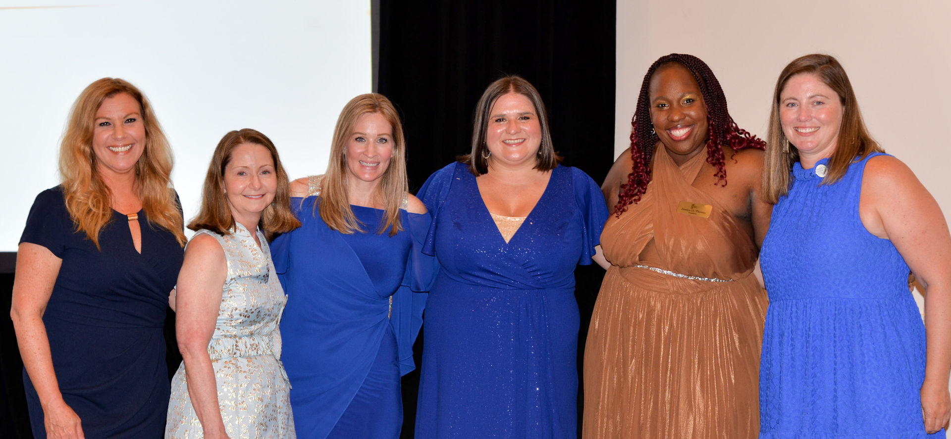 Six women in blue and gold dresses at a conference, all past FAWL Presidents
