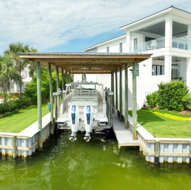 Powerboat on a covered lift next to a waterfront home.