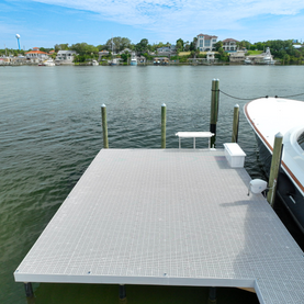 Small gray floating dock project on a waterway with a boat