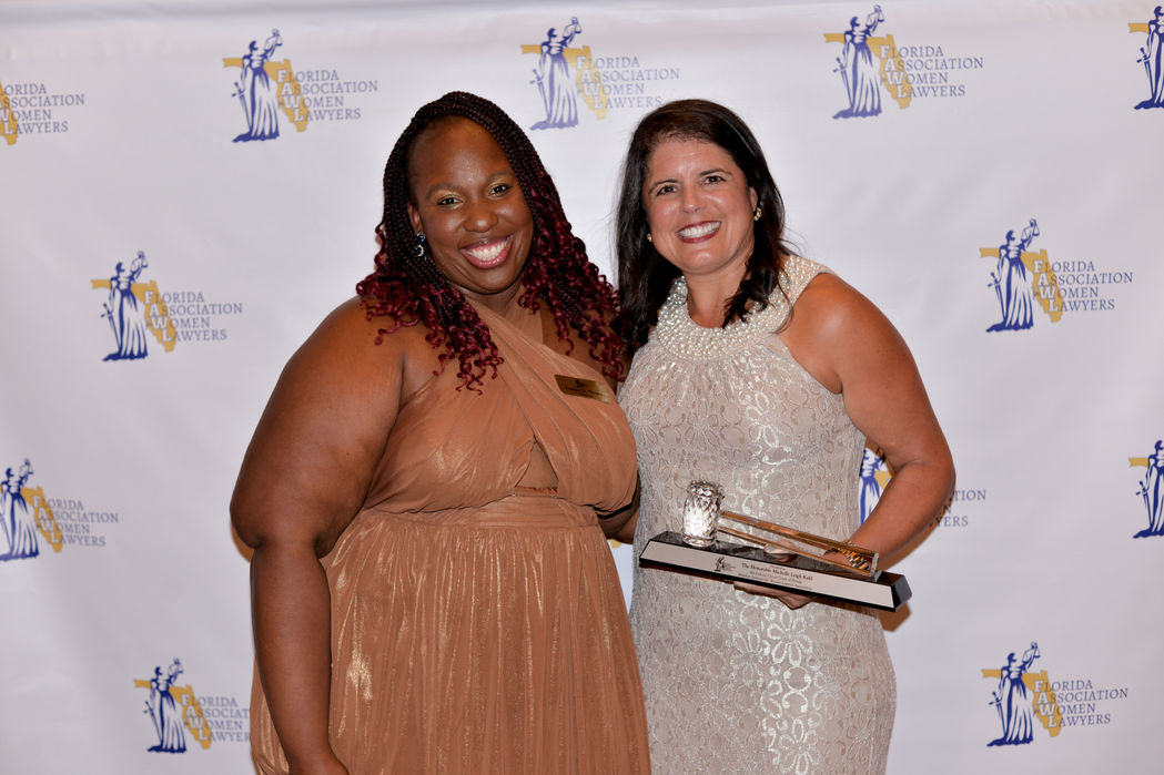 Two women at awards ceremony, holding award