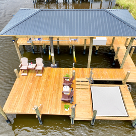 Wooden dock with covered boat lift and seating area.