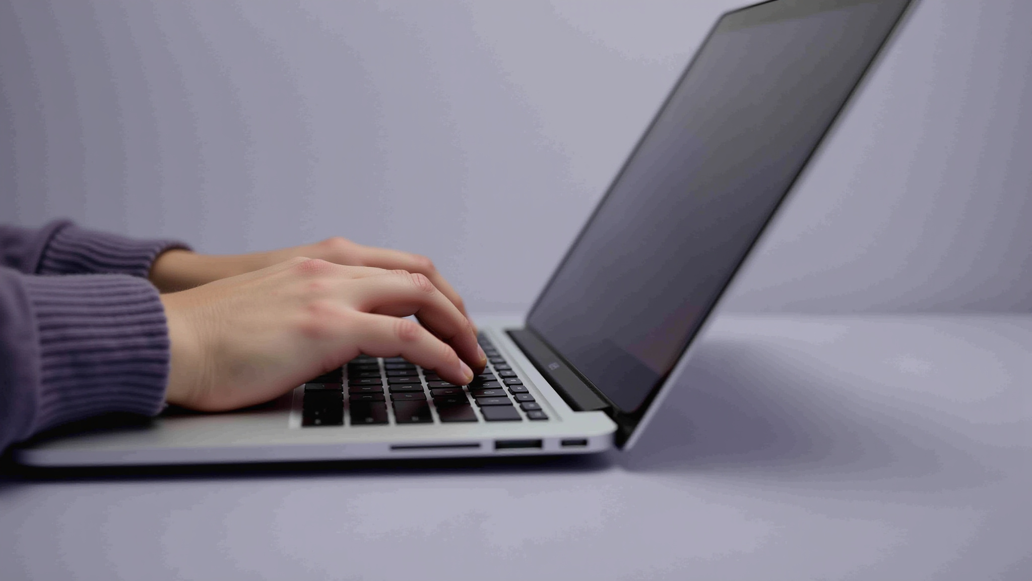 Hands typing on a laptop, focused work on a sleek modern device.