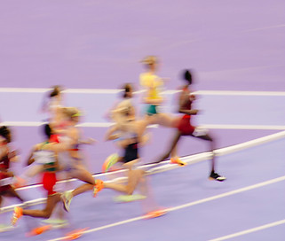 Blurred image of runners on a lilac race track