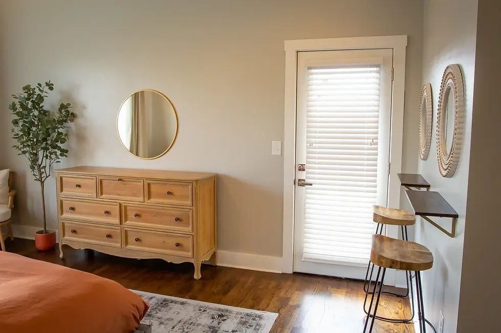Elegant rustic bedroom at Underwood Manor with natural wood dresser, gold mirror, and wooden chairs showcasing Tennessee