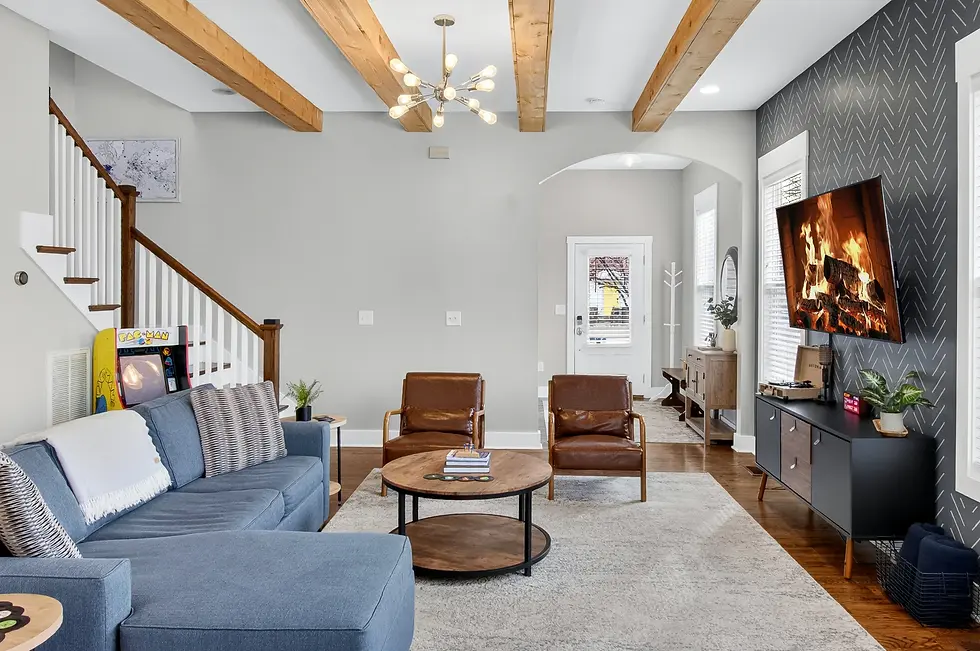 Modern living room with blue sectional, leather chairs, fireplace, and exposed wood beams