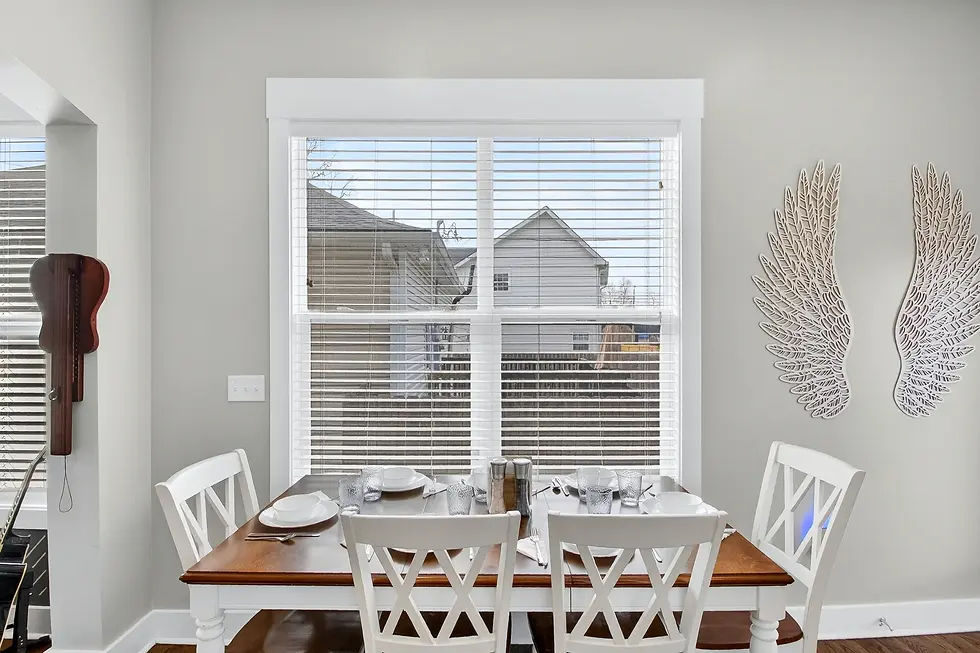 Modern dining room with wooden table and white chairs overlooking Nashville neighborhood, exemplifying local restaurant
