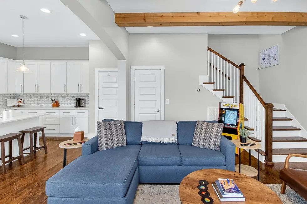 Modern open-concept living room with blue sectional sofa and white kitchen cabinetry in Nashville TN bachelor party luxury