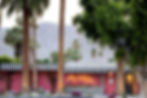Palm trees in front of a pink building with black-and-white striped awning. The Muse Hotel: Perfect choice for pink hotels in Palm Springs