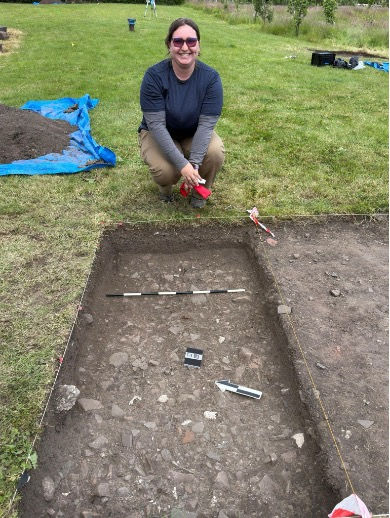 Me with the photo setup for when we discovered context 003. We have a meter stick, a north arrow, and a label for the context number. Splitting the trench is called a sondage! Photos credit to Professor BH.