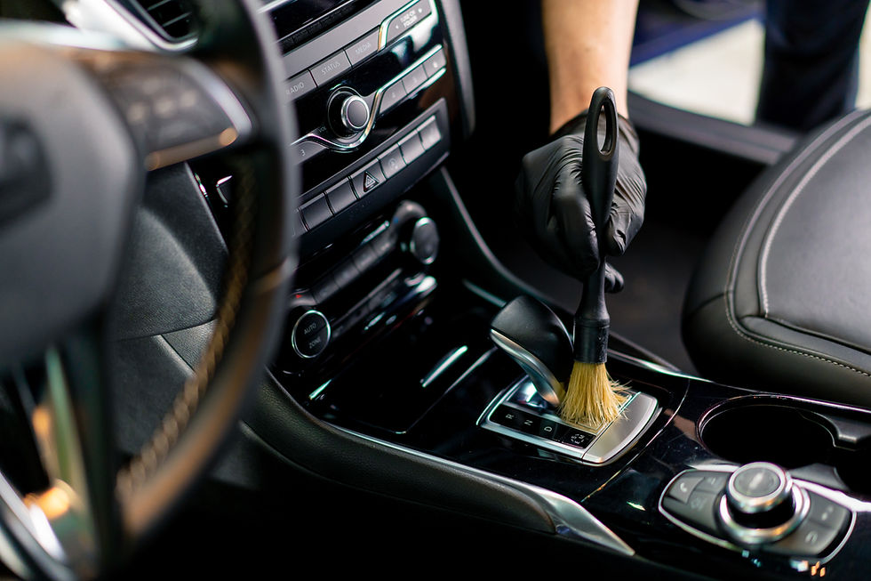 A car wash worker carefully cleans the interior of a luxury car with a rag a brush vacuum 