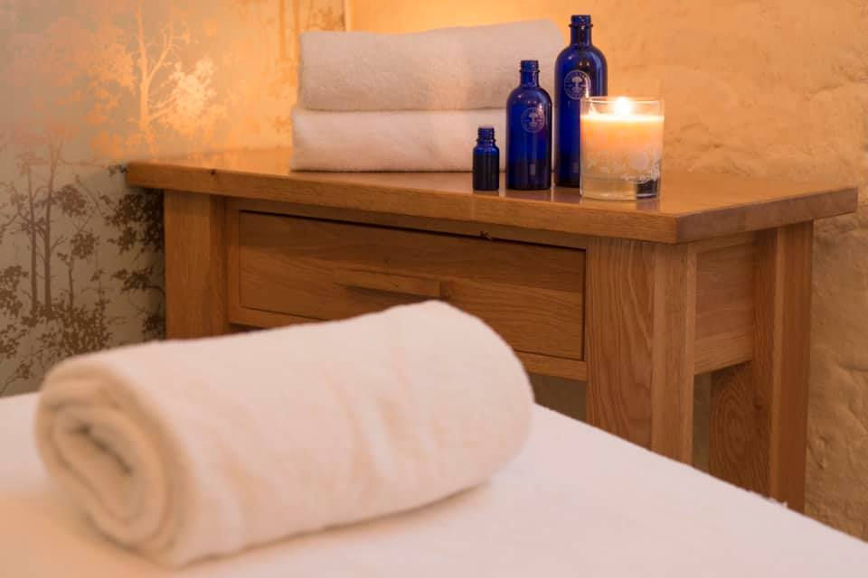 Treatment room bed with rolled up towel pillow and a lit candle