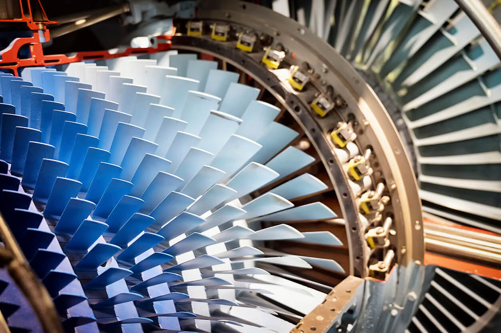 Close-up of a jet engine turbine with blue and silver blades. The intricate fan design creates a dynamic, industrial feel.