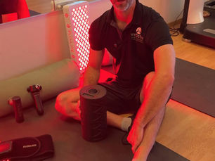 Scott Webster visar återhämtningsutrustning med foam roller och rött infrarött ljus i träningslokalen.