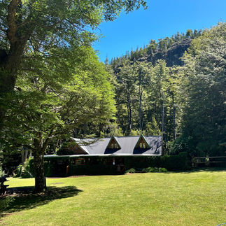 casa de montaña rodeada de arboles del Refugio El Retamal en circuito troncal del bolson pasando del cajon del azul en argentina