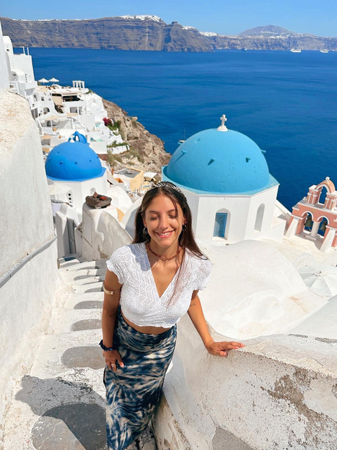 mujer joven vestida de blanco y azul en spot famoso para fotos en la isla griega santorini
