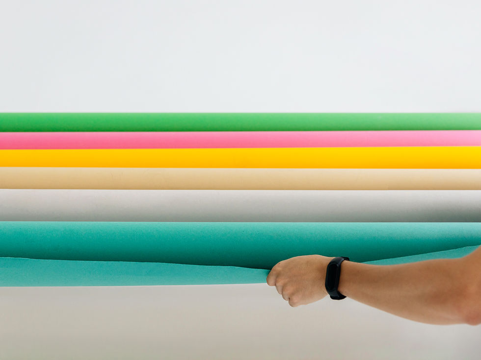 Rolls of green, pink, yellow, tan and teal colored paper backdrops in the DropBy studio