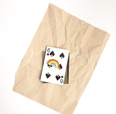 needleminder secured to a playing card, on a square of brown paper