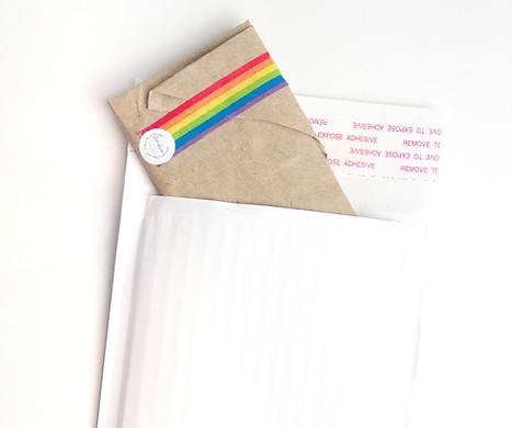 brown paper packet, secured with rainbow tape, in a white paper envelope