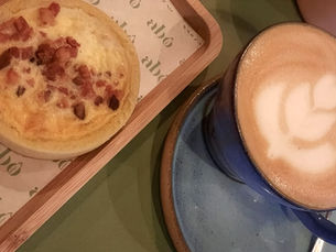 mesa com um café e um quiche coberto por bacons