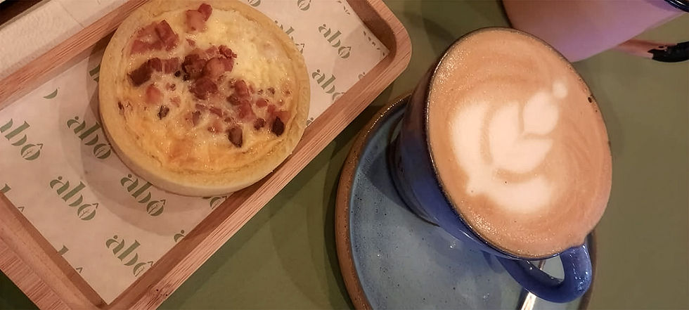 mesa com um café e um quiche coberto por bacons