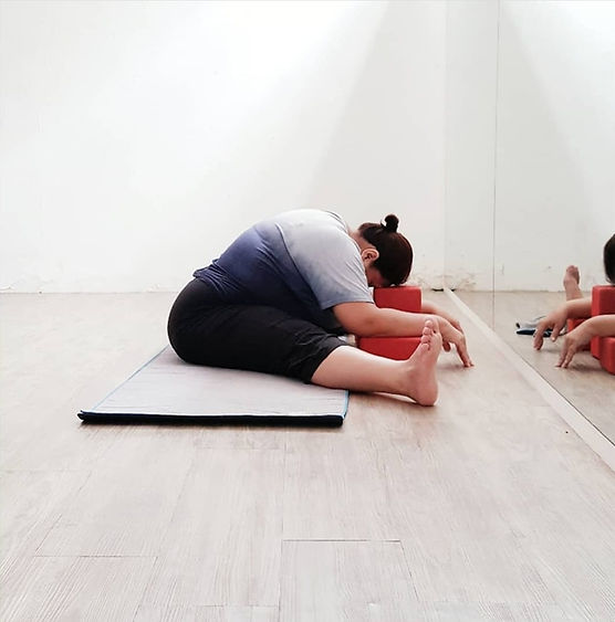 Bigger-bodied student in seated forward bend (paschimottanasana) yin yoga style