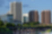 Daytime photo of several Richmond city skyscrapers with bridge and water in foreground.
