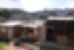 Foto de uma comunidade atendida pelo Bumerangue do Bem. No primeiro plano vemos o tipo de construção de barracos de bloco com fechamentos em madeira ou alumínio e telhas de amianto como telhado. Logo atrás, dá para se ter uma idéia da dimensão do bairro formado que toma dois morros imensos, entre poucas árvores que resistem entre as casas.