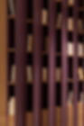 Seascape bookcase in maroon, featuring unique curved shelves that change appearance when viewed from different angles.