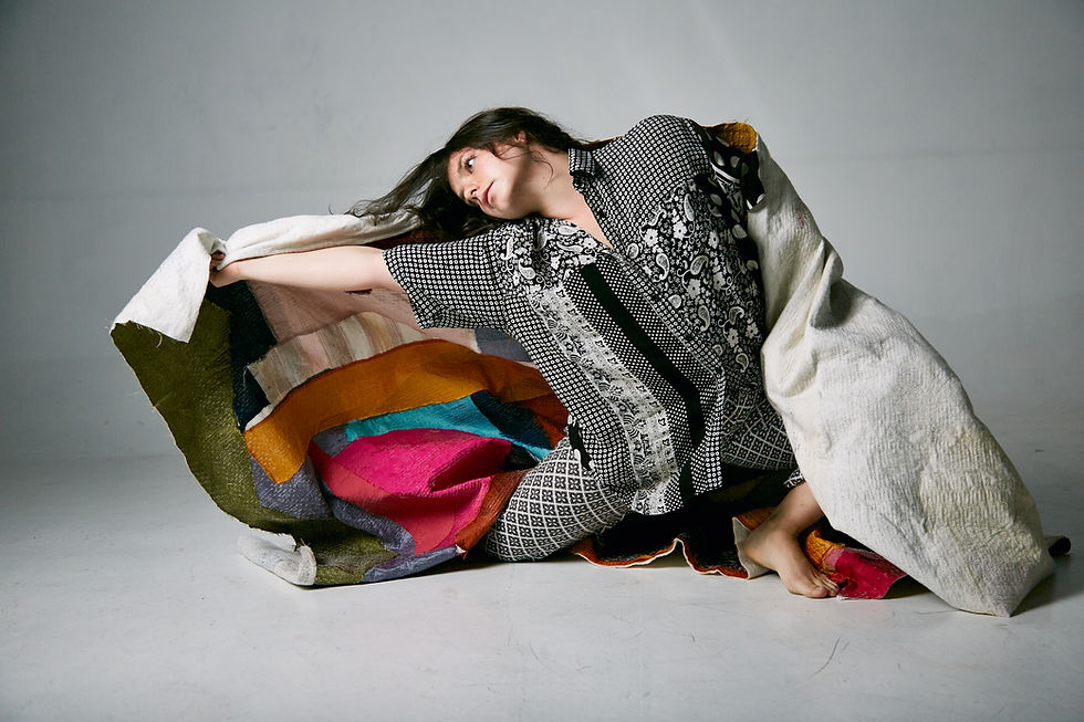 Dancer from The Moving Architects poses with a colorful quilt.