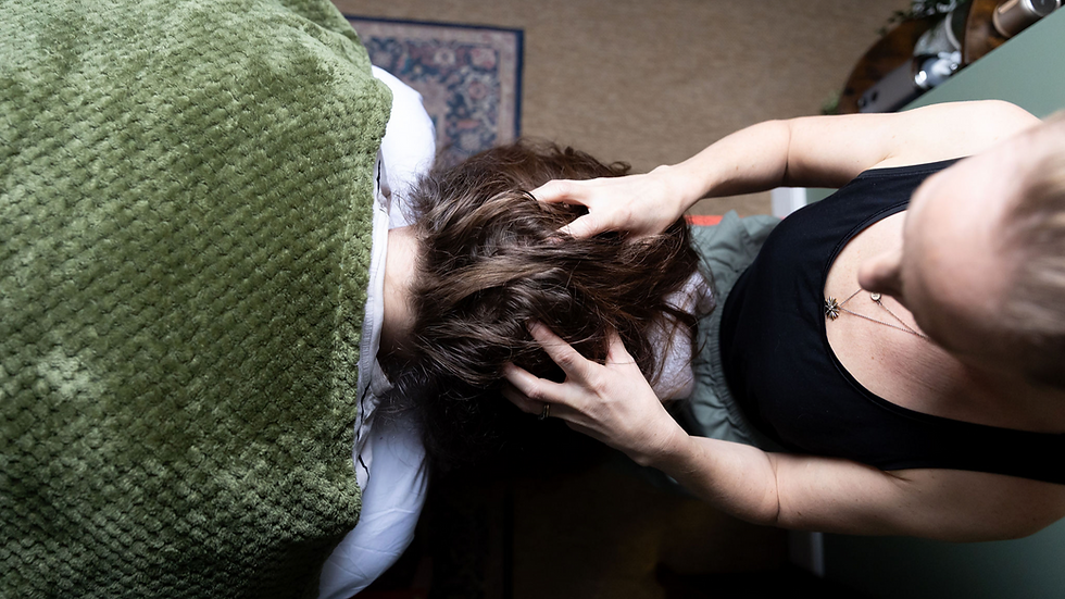 Top view of a woman giving a scalp massage to another person lying on a bed with a green blanket, calm home setting