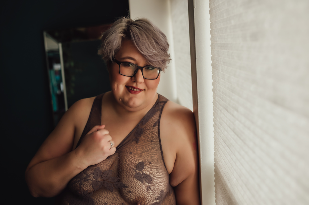 woman in lavender bodysuit leans against wall