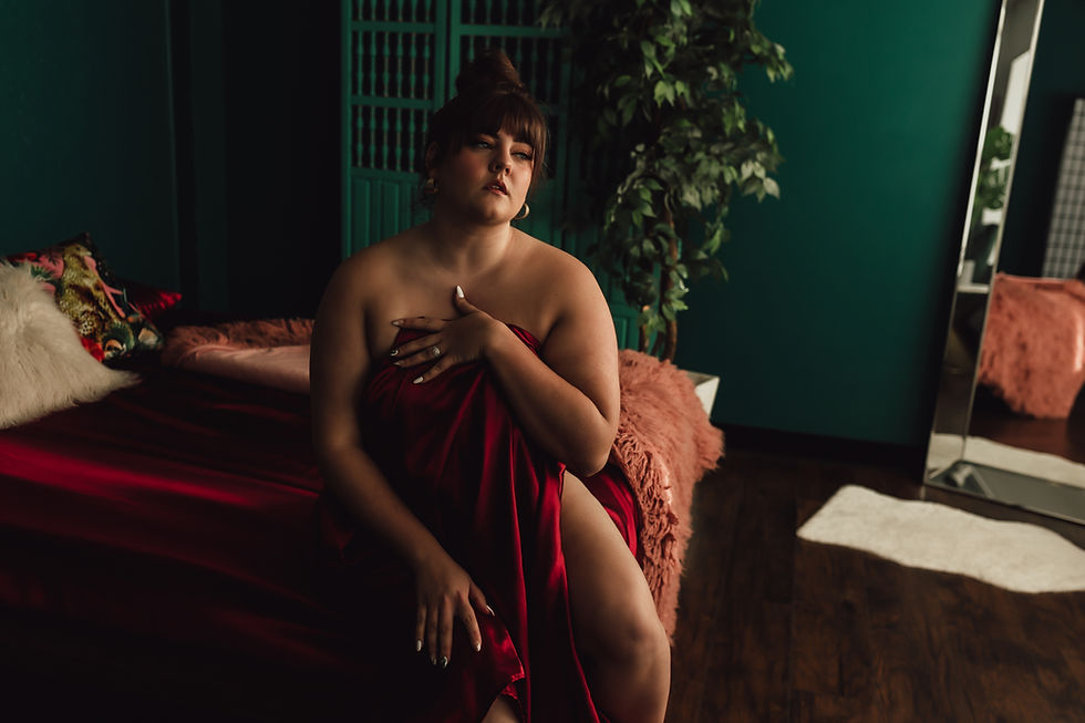 woman on corner of a bed with a sheet over her
