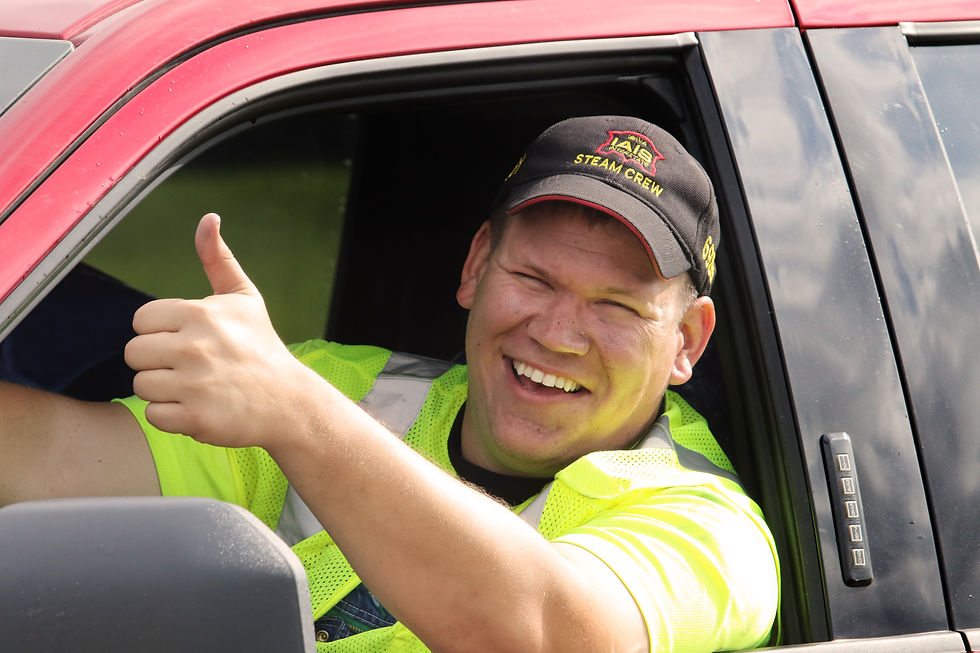 Steam crew person wearing a safety vest giving a "thumbs up" gesture.