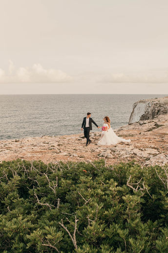 Brautpaar läuft an Meeresküste bei Destination Wedding