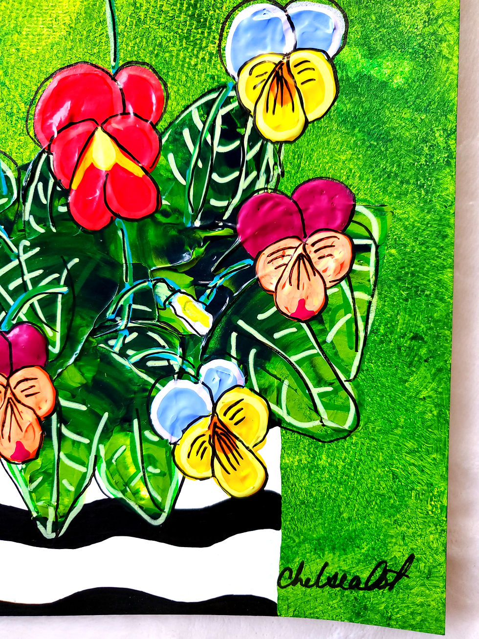Thumbnail: Colorful pansies in bloom with thick textured leaves in a black-and-white flower pot, set against a green background with dar