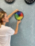 Woman hanging a completed CircZle circular jigsaw puzzle by Circular Puzzles—art you can frame.