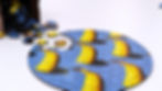 Phallacy Circular Puzzle — CircZle circular jigsaw puzzle featuring blue and yellow pieces spilling from a wooden box.
