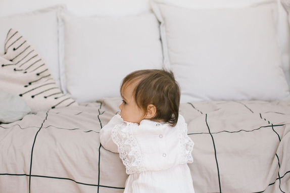Tendre photographie d'un enfant regardant à sur le côté, capturée par un photographe spécialisé dans les portraits de famille, dans une chambre paisible.