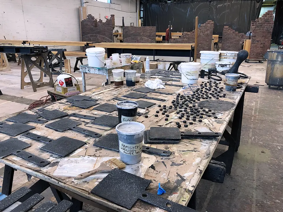Decorative hardware laid out on a table, scenically finished as wrought iron for the Broadway production of Hamilton by Hudson Scenic Studios.