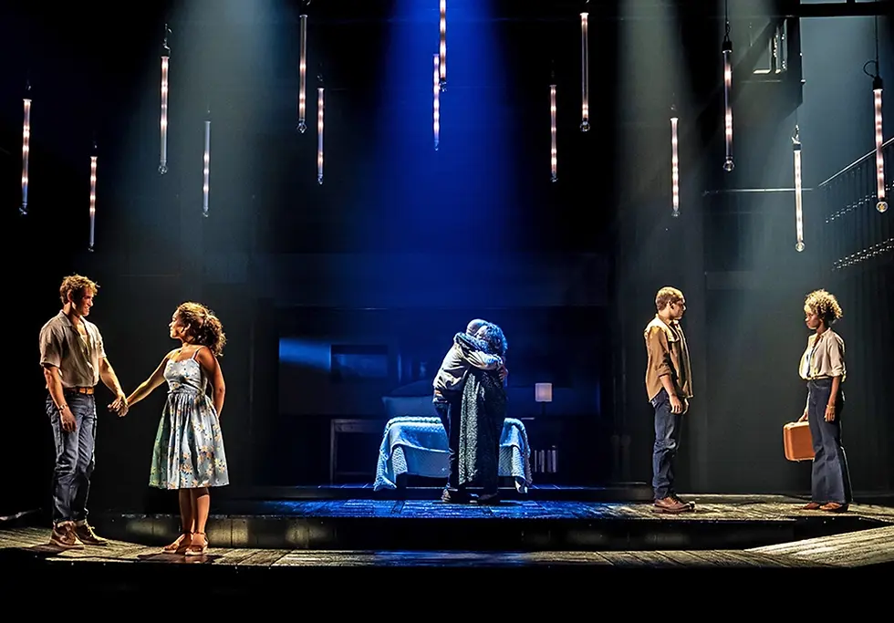 The cast of The Notebook the musical performs on deck scenically finished as weathered wood planks with a pool at the center and a skeletal house set behind.