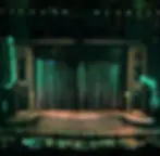 The pre-show stage of the Broadway revival of The Rocky Horror Show, with gold-dusted proscenium towers on both sides of a rounded stage with a deck scenically finished as weathered wood.