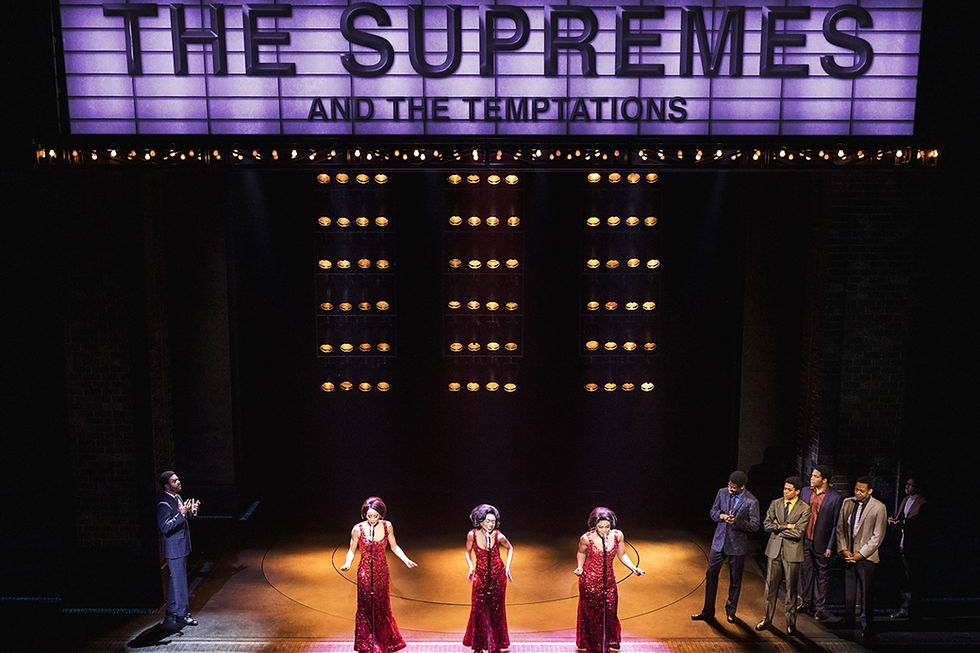The original Broadway cast of Ain't Too Proud perform on a set with a marquee above that reads, "THE SUPREMES AND THE TEMPTATIONS" and three vertical rows of lights behind.