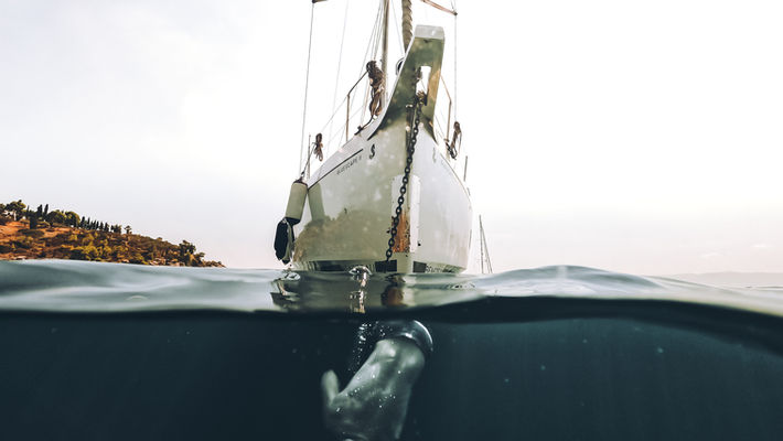 Freediver on the bow of a sailing boat