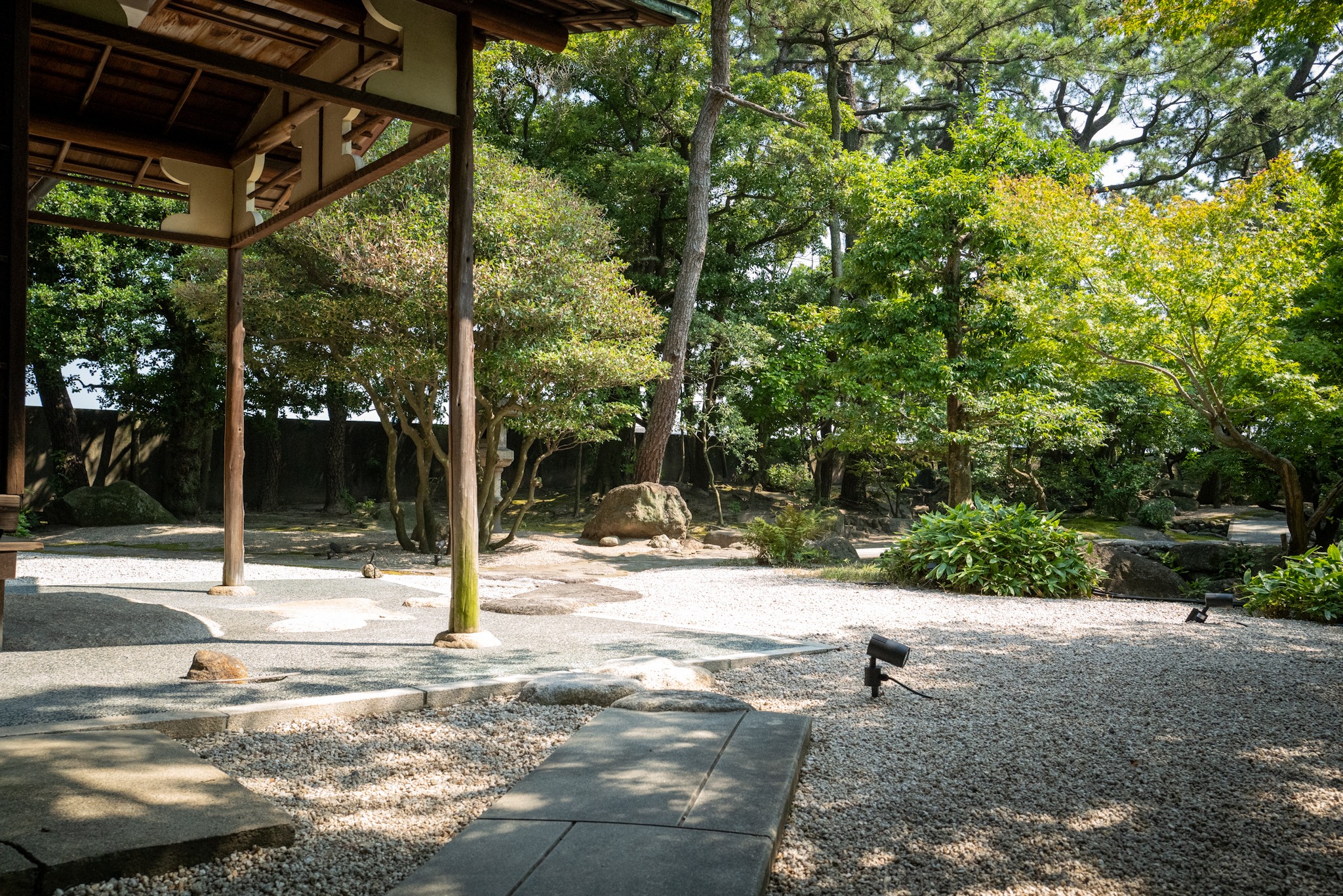 建物の軒下から見た白砂利と石組み、静かな眺め
