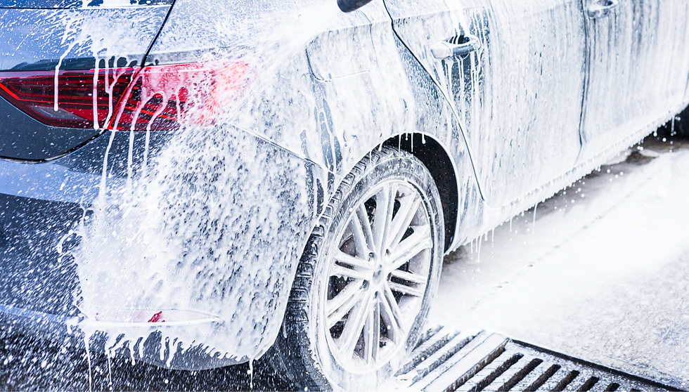 A car coated in thick soap foam is parked at a local service station Water drips from the