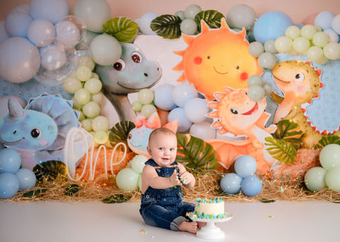One year old boy demolishing his cake against a Dino themed backdrop during his first birthday portraits with Milk & Honey Photo Co in Northwest Indiana.