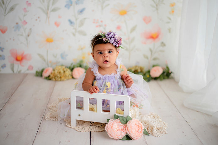 Six-month baby portrait surrounded by soft floral decorations in a Northwest Indiana photography studio.