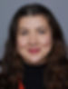 Smiling woman with long brown hair and a black top against a gray background. Mood is calm and positive.