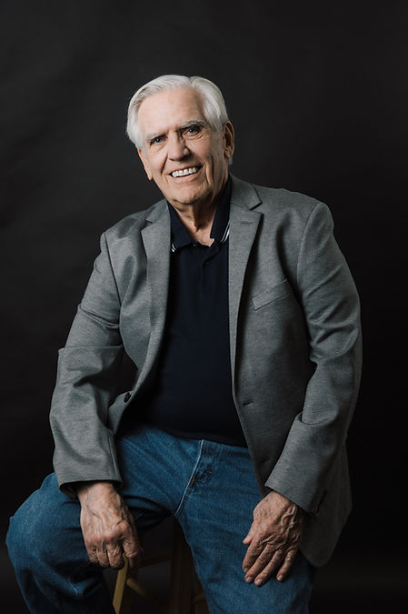 photo of author Roger Skrypczak wearing a grey blazer and smiling.