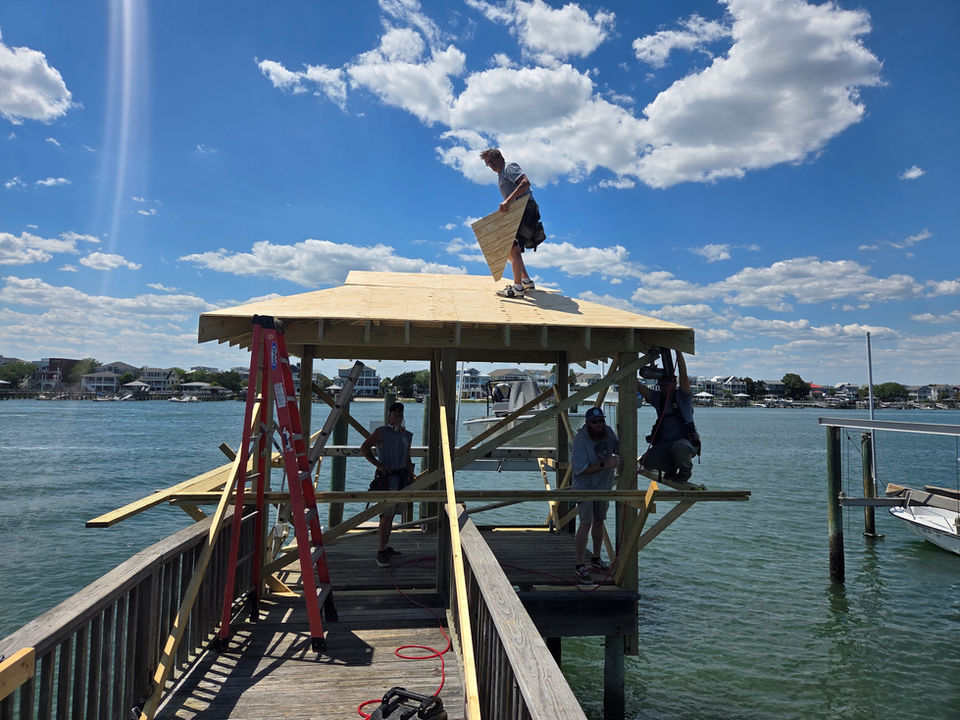 Construction workers building a wooden gazebo on a dock